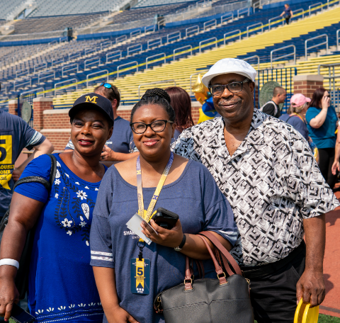 Three people smiling at the Michigan Football Stadium