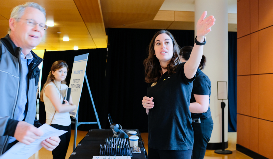 A female conference staff member directs a male attendee to his destination