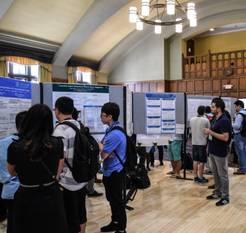 People viewing large poster board displays in a large conference room.