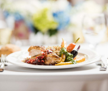 Plated dinner setting with chicken and colorful, roasted vegetables.