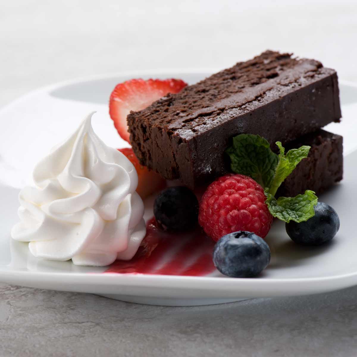 Plate with fudge cake, berries, and cream.