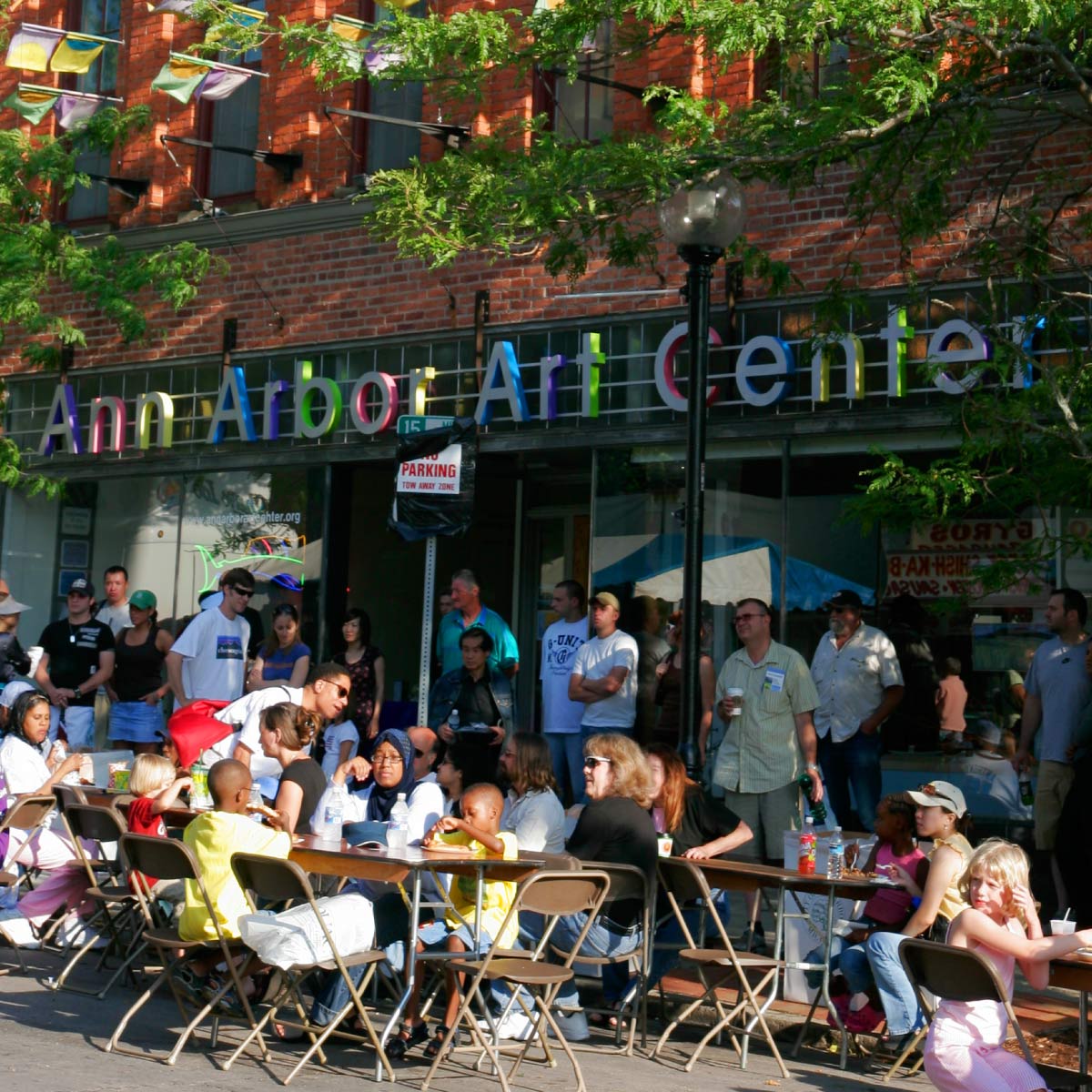 People sit at tables outside the Ann Arbor Art Center.