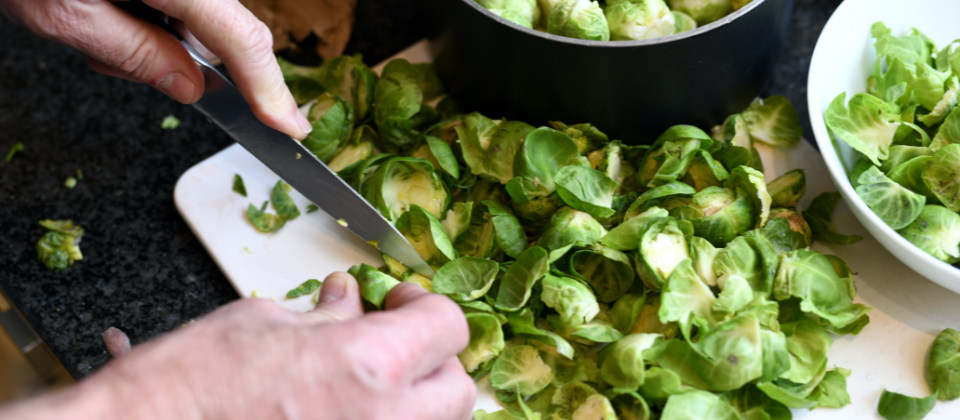 Chef using knife to chop Brussels sprouts.