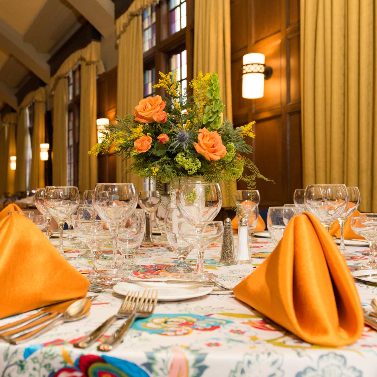 Table set for event with flower centerpiece, folded napkins, and wine glasses.