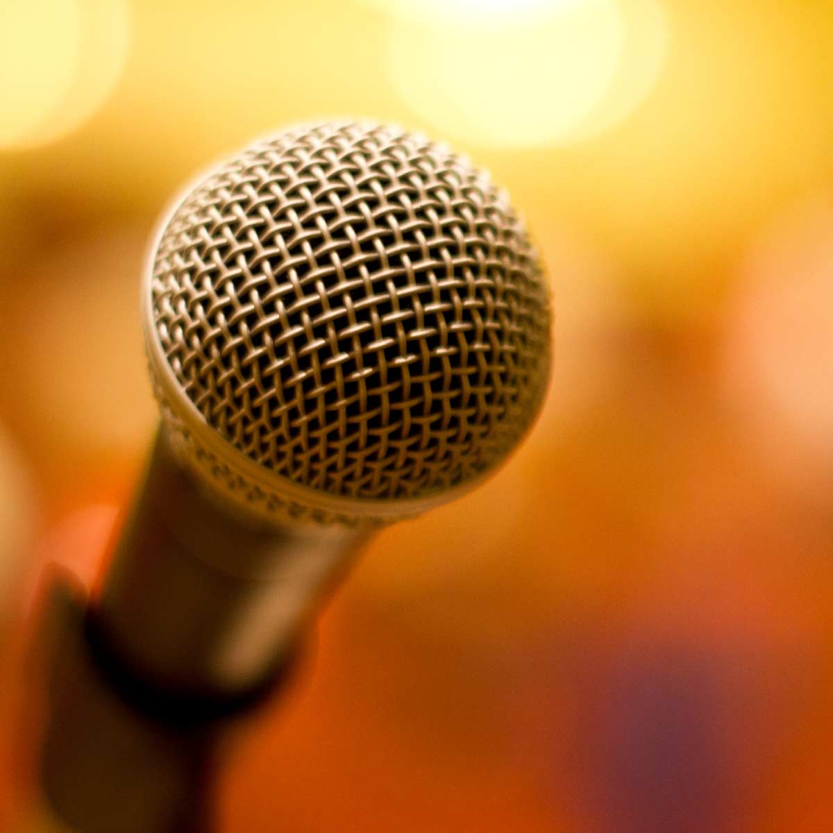 Close up of a microphone on an orange background.