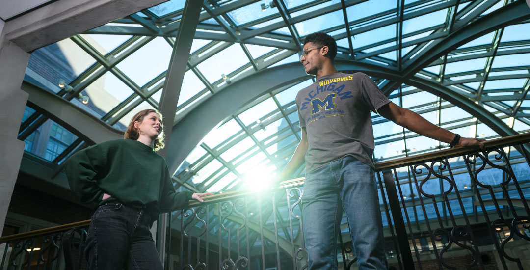 Two students chatting in a building under the sunlight